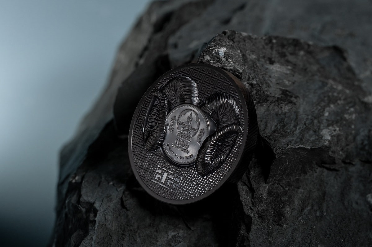 Fine silver collectible coin featuring intricate ram's head design, with Chinese cultural motifs, on a dark textured background.
