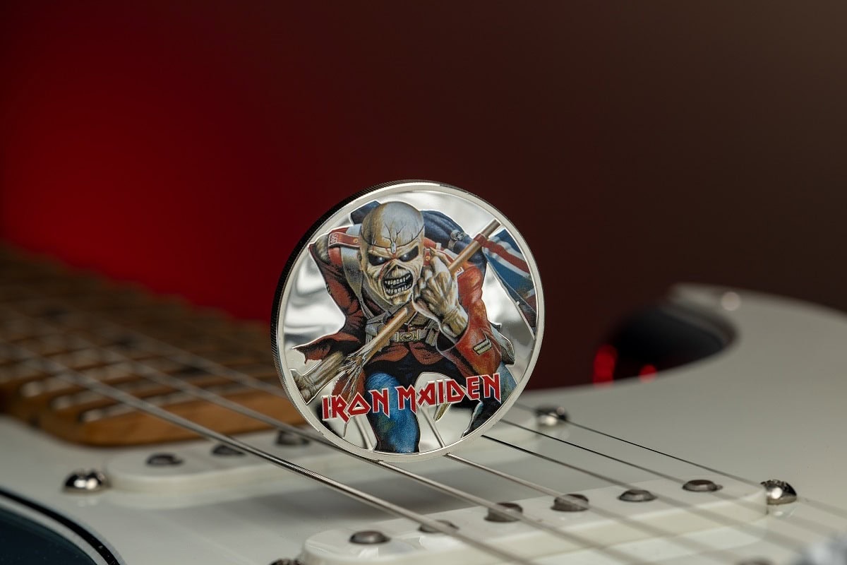 Iron Maiden collectible coin featuring the band's mascot, Eddie, wielding a weapon, set on an electric guitar background, showcasing detailed artwork and vibrant colors.