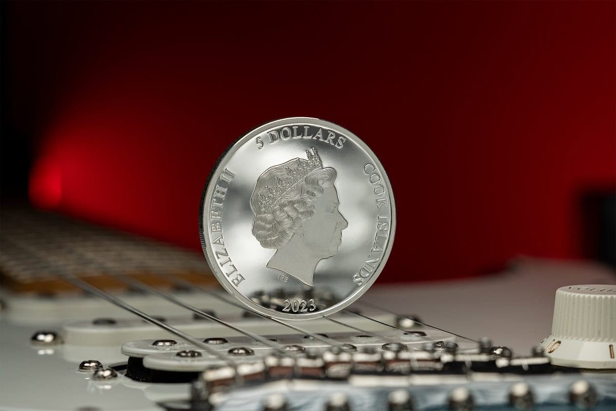 Shiny silver 2023 Cook Islands 5 Dollars collectible coin standing on a musical keyboard close-up.