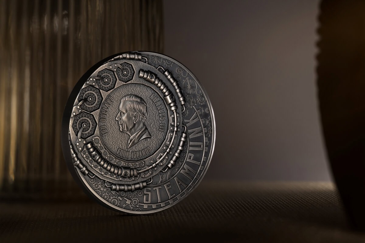 Engraved face of a commemorative coin with intricate mechanical details and the text "STEAMPUNK" visible at the bottom.