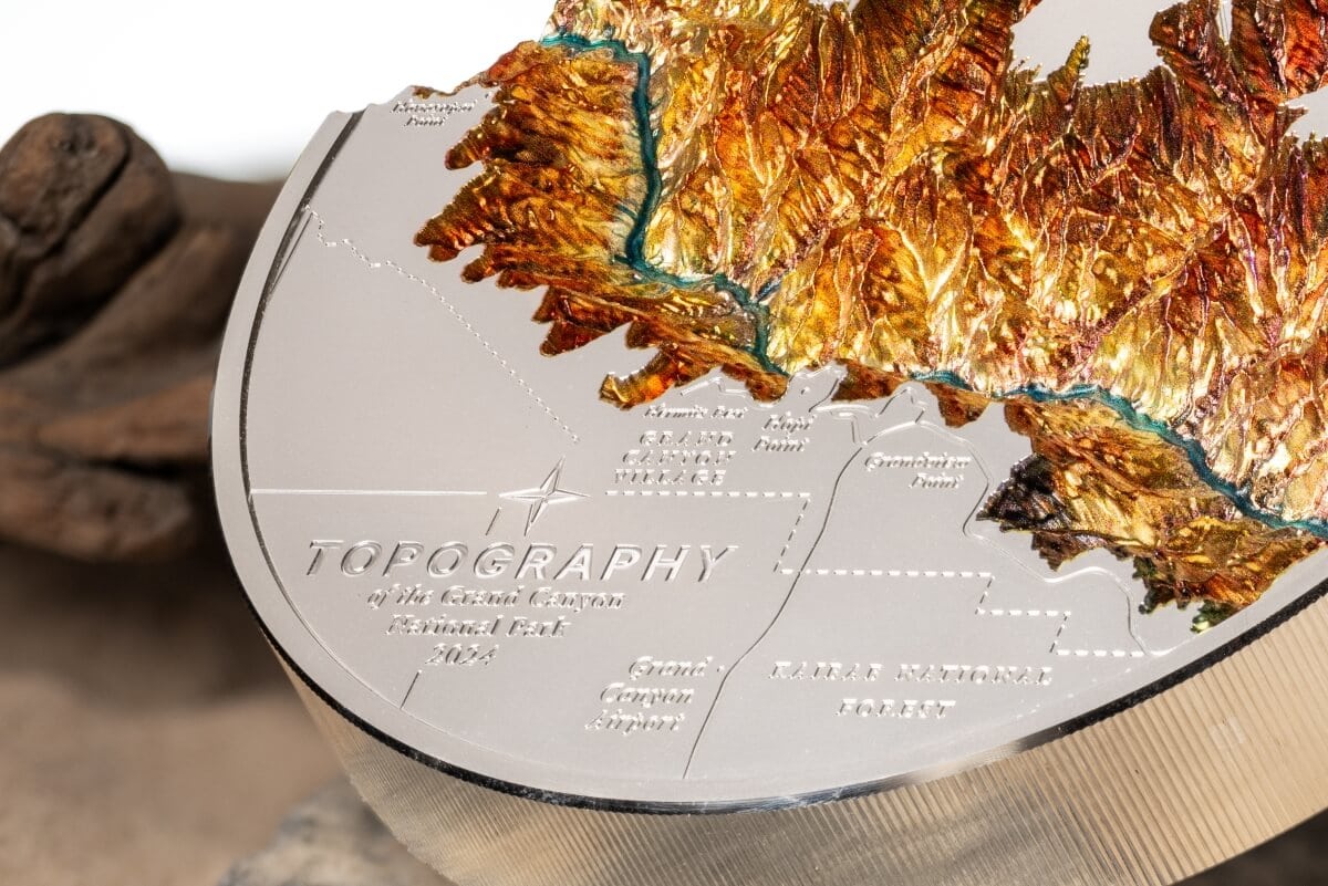 Golden Bear Mountain Topography collectible coin, 2023, with detailed relief of the Sierra Nevada range, metal map engraved with labels of geographic features, mounted on a display base.