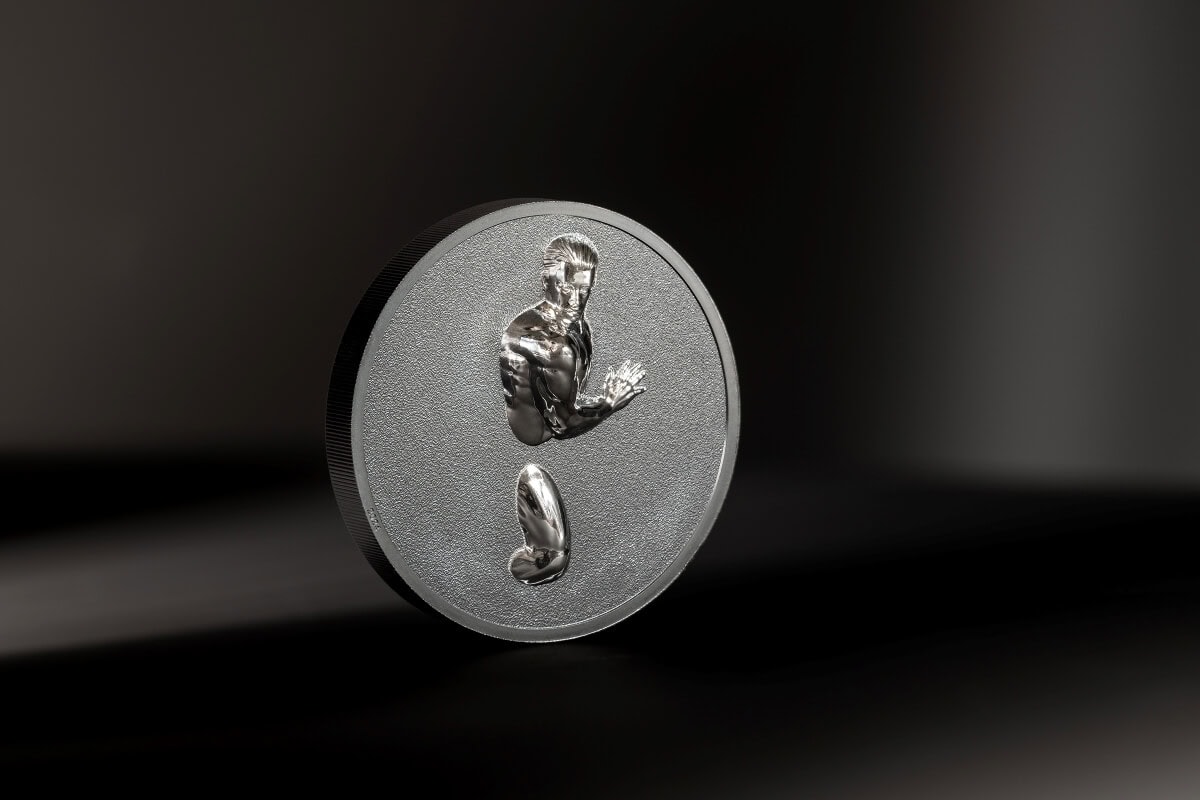 Shiny silver collectible coin featuring a muscular man's torso and arm with a textured background, showcasing detailed craftsmanship, on a dark surface with soft lighting.