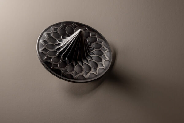 Modern black and silver collectible coin featuring intricate geometric lattice design, mounted on a textured beige background. Perfect for numismatic collectors seeking unique, contemporary currency art.