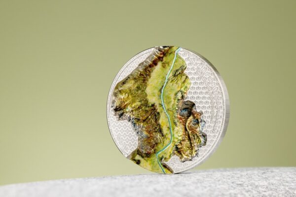 A close-up of a Liechtenstein 2024 1 oz silver coin with a silk finish, featuring a colorful design of a train in a landscape.