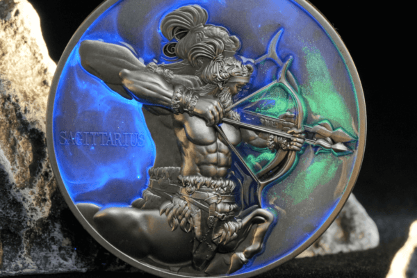 Intricately designed silver collectible coin featuring Sagittarius archer with a bow, showcasing detailed craftsmanship, vibrant blue and green background, and the inscription "SAGITTARIUS" on the left side.