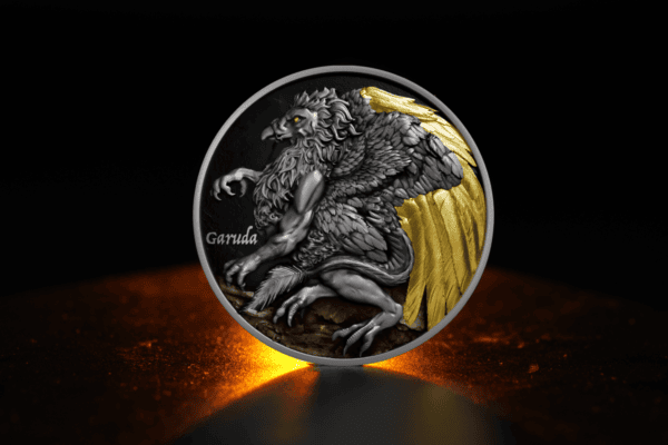 Garuda coin with black and gold details, featuring a detailed depiction of the mythical bird from Indonesian folklore, mounted on a textured base, high-quality collectible metal piece.