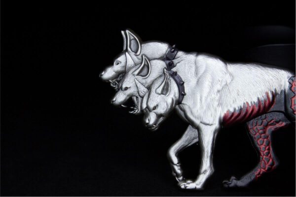 Close-up of the 2025 Cerberus silver stacker showing three snarling dog heads with vivid colorized eyes, sharp fangs, and antiqued silver texture.