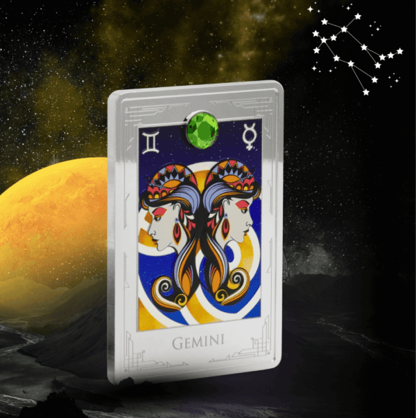 Gemini zodiac coin with colorful twin female faces and a green gemstone at the top, set against a cosmic background with stars and planets, commemorating the astrological sign.