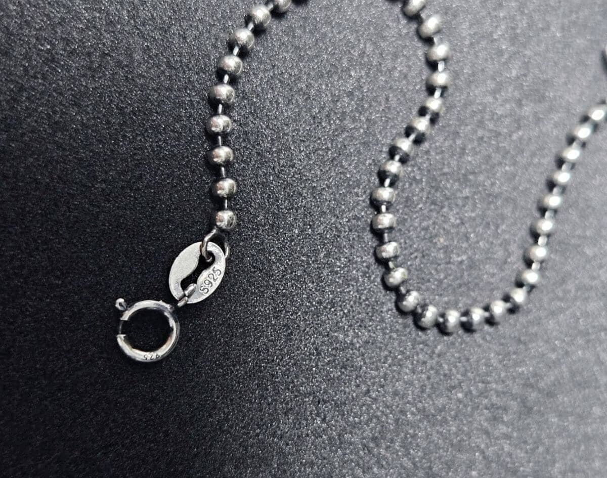 S925 sterling silver jewelry chain with spring clasp on black textured background.