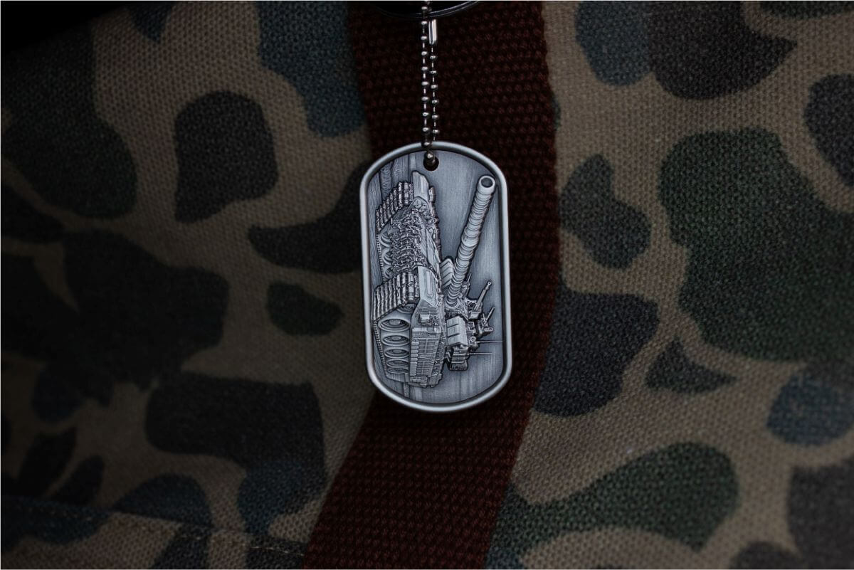 Dog-tag military badge featuring a detailed tank illustration on a camouflage fabric background.