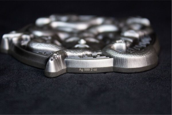 Side view of the 2025 South Korean Serpent Crown Medusa 2 oz Silver Antiqued High Relief Stacker showing layered edge with coiled serpent textures; thick profile and antiqued finish emphasize sculptural depth on dark surface.