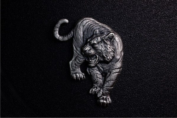 Studio-lit front view of the 2025 South Korea Tiger 1 oz Silver Antiqued High Relief Shaped Medal showing prowling tiger with open mouth and raised claw against black background; intricate fur, muscle detail, and antiqued silver texture emphasize high-relief design.