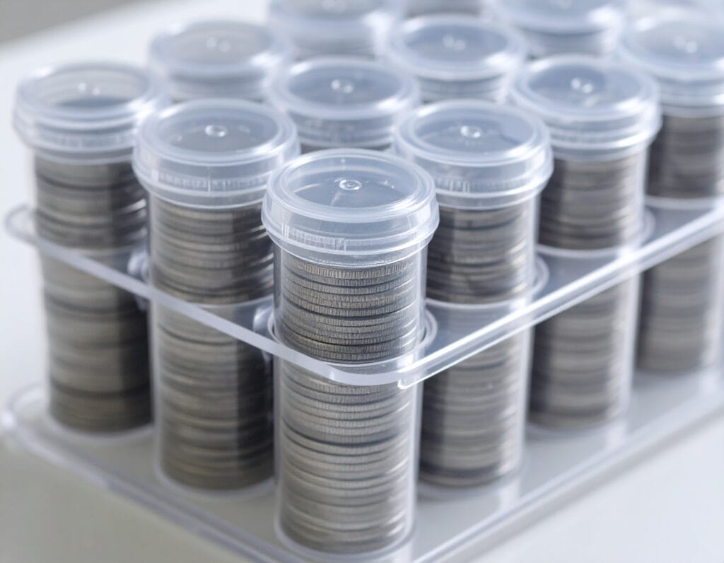 Clear plastic tubes, stacked and filled with shiny silver coins, against a light background.