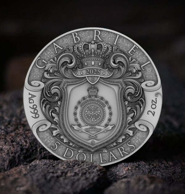 The back of a 2025 Niue "Herald of Salvation - Gabriel" antiqued silver coin, featuring the inscription "GABRIEL," specifications, and a central coat-of-arms design, resting on a dark, textured rock.