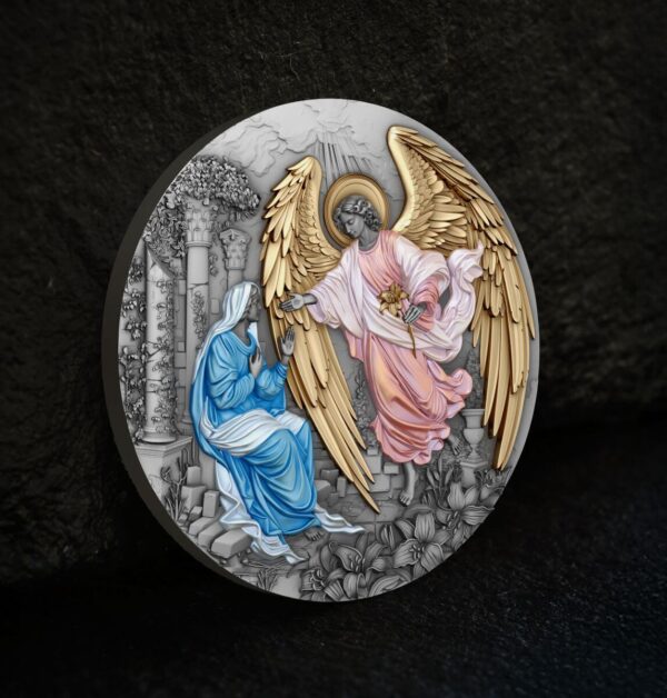 A close-up, angled view of the front of the Niue "Herald of Salvation - Gabriel" coin, showing the Annunciation scene with its antiqued and gilded details against a dark background.