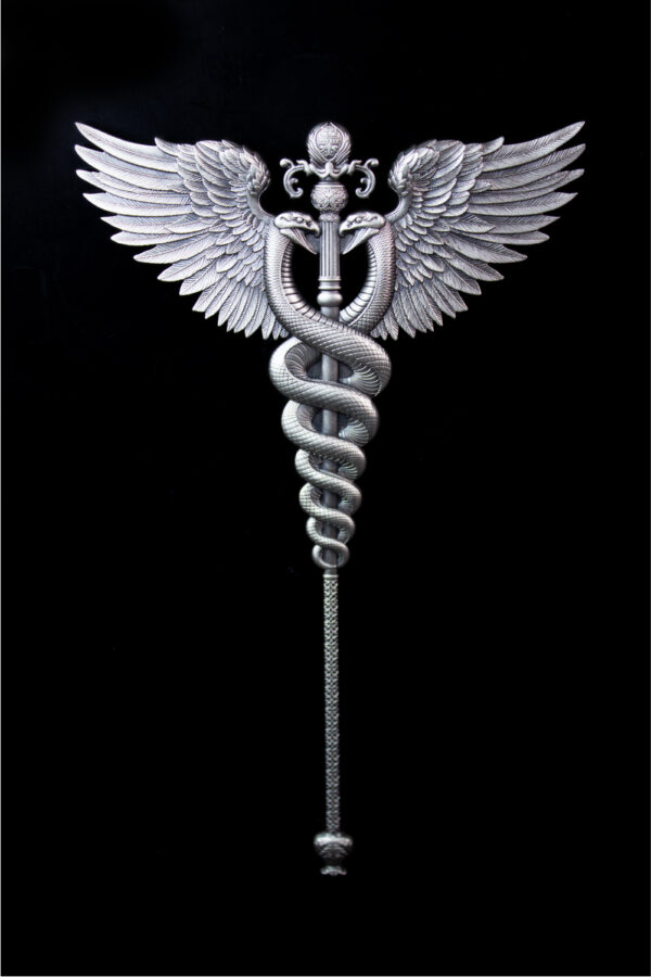 A close-up, front-facing image of a silver, antiqued medal in the shape of a winged staff, with a snake coiled around it and a sphere at the base.