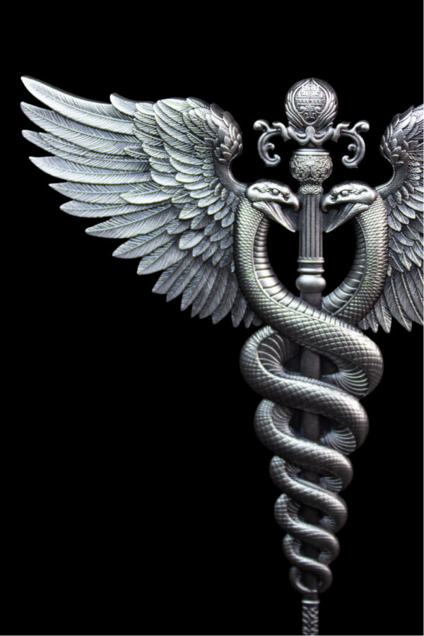 A close-up, highly detailed image of the top portion of a silver, antiqued medal featuring a winged staff with a snake coiled around it.