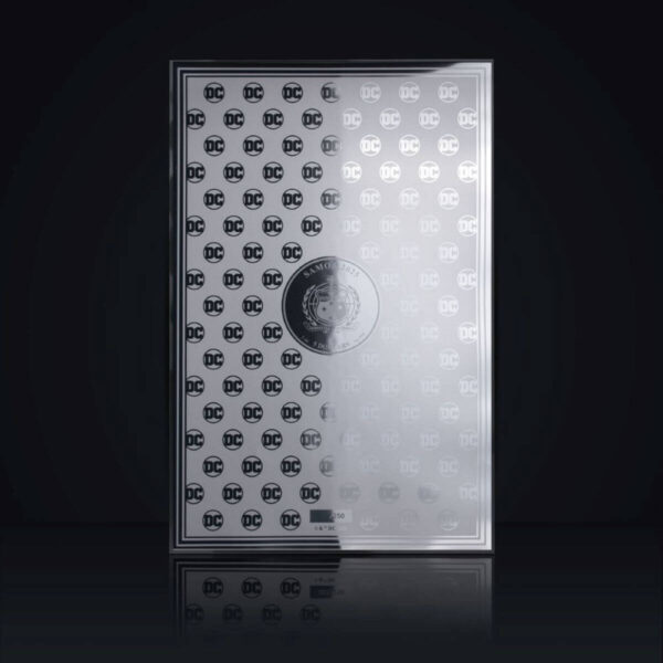 The reverse side of a silver foil coin from Samoa, featuring a repeating DC logo pattern, set against a dark background with a reflection.