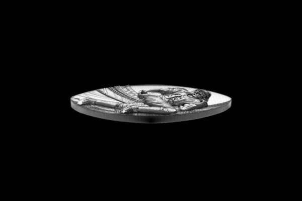 A shiny silver collectible coin featuring a detailed depiction of a seated figure with a helmet, engraved with fine lines.