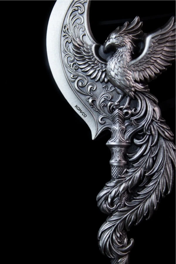 Intricate collectible silver coin featuring a detailed eagle with outstretched wings and ornate design elements, with "KOMCO" inscription visible.