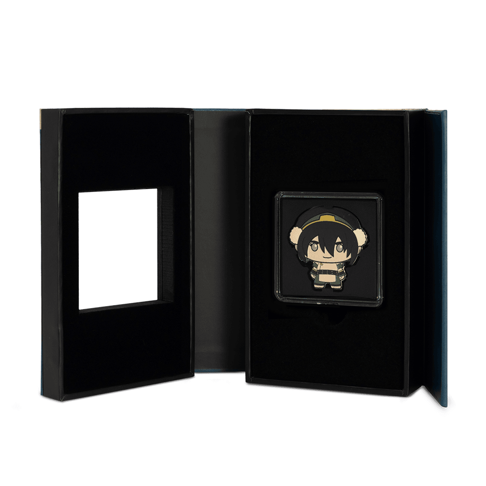 An open black presentation box for the Toph Beifong chibi coin, revealing the coin in its capsule on the right side and an empty square cutout on the left.