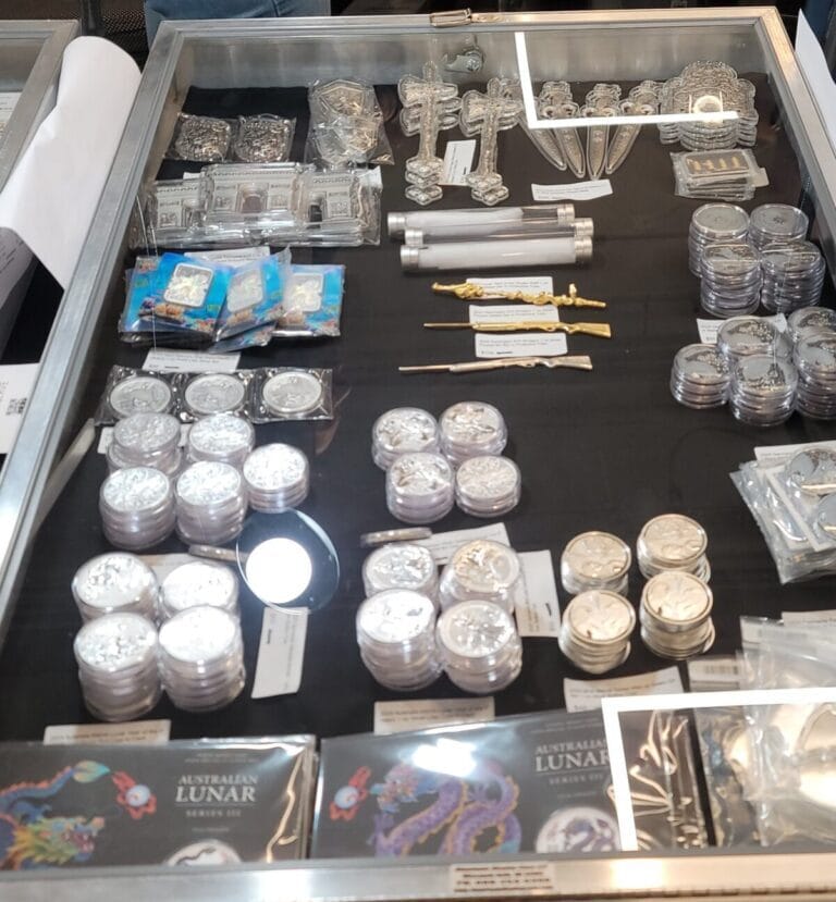 A close-up view of a display case containing multiple small trays of antique or collectible coins, organized for viewing.