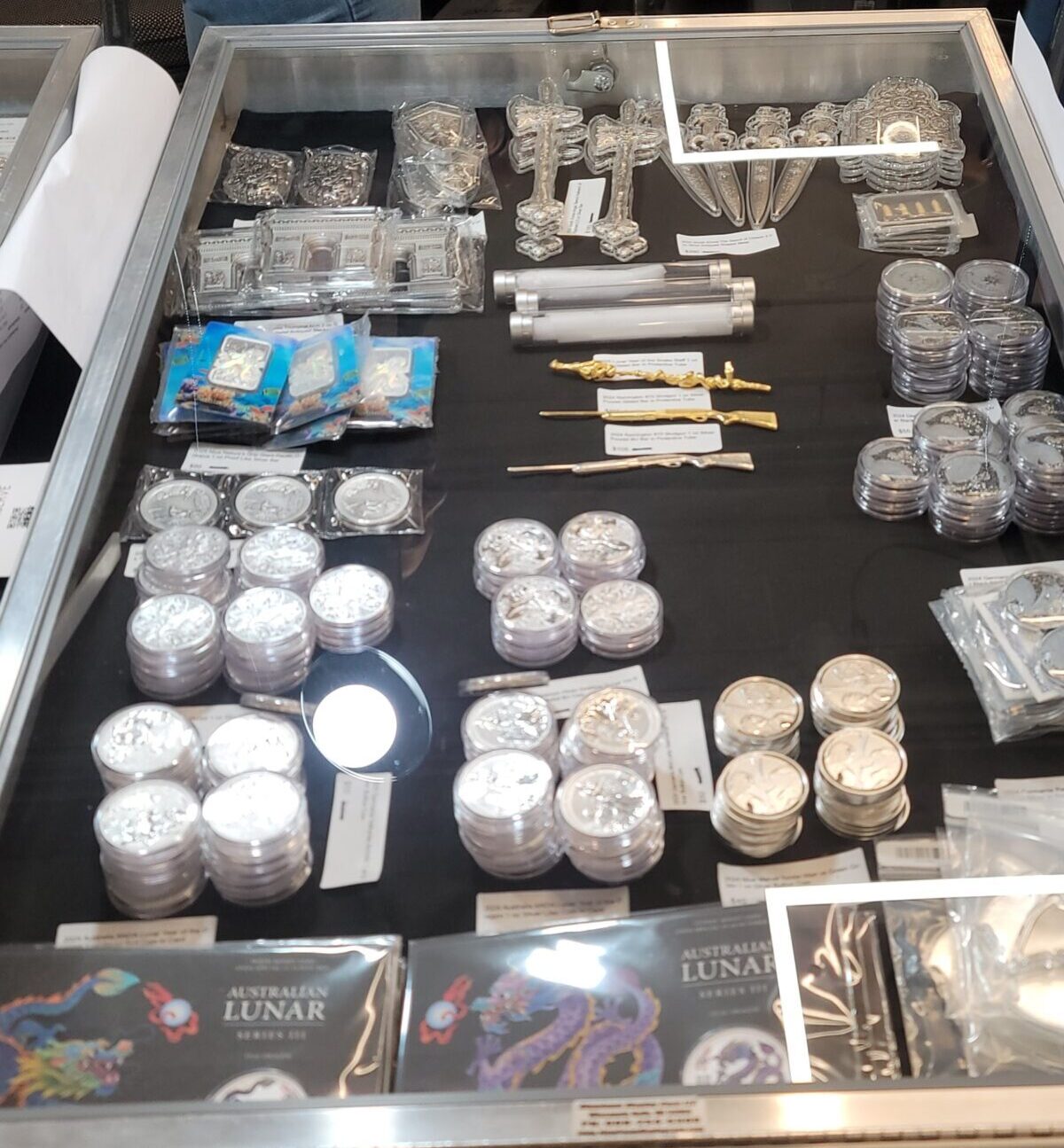 A close-up view of a display case containing multiple small trays of antique or collectible coins, organized for viewing.