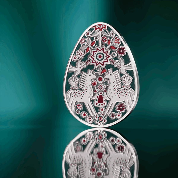 Intricate silver and red decorative egg with horses and floral patterns, luxury collectible item for Easter or special occasions.