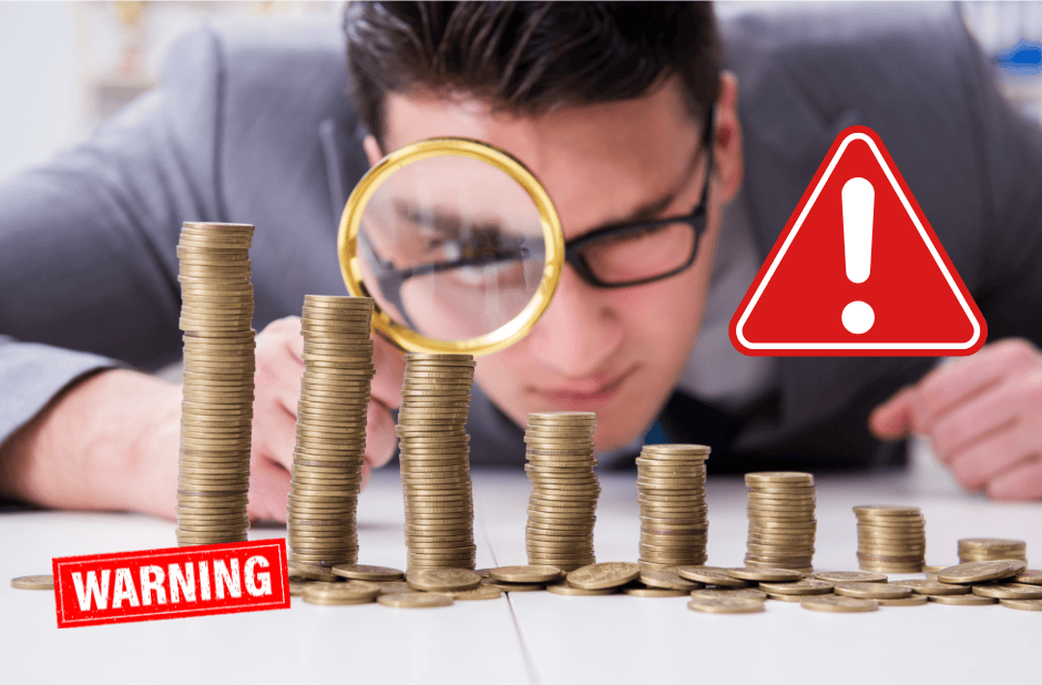 Stacks of coins with warning and alert symbols indicating financial risk or loss.