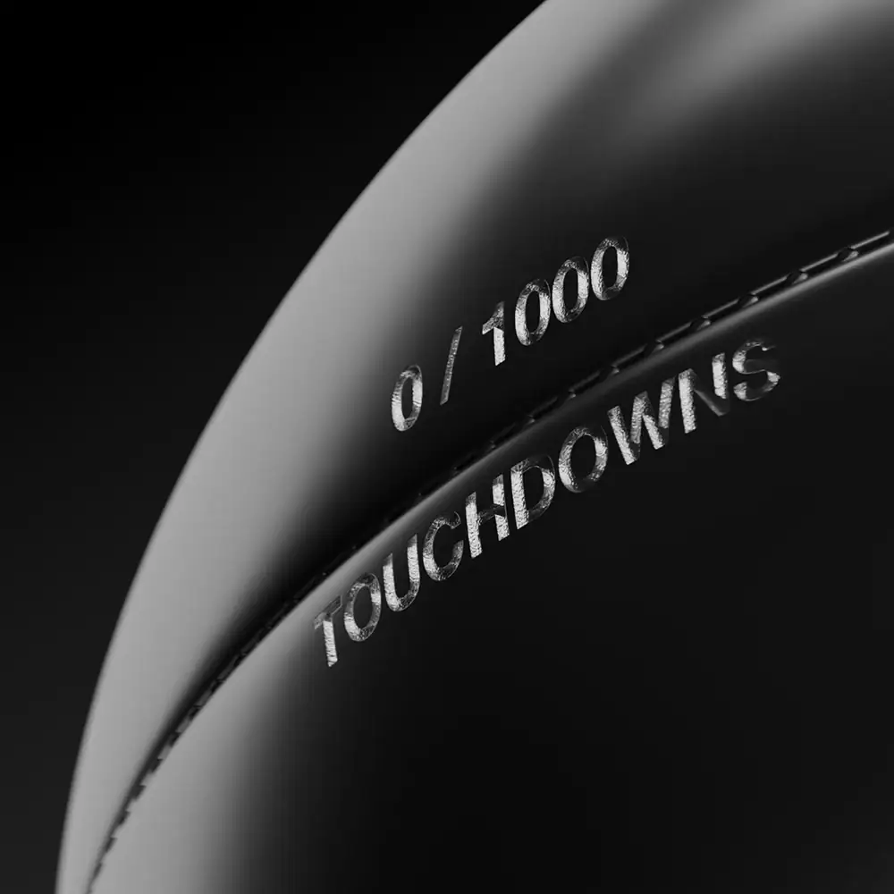 Shiny silver coin with engraved text "0 / 1000" and "TOUCHDOWN" on a reflective surface.