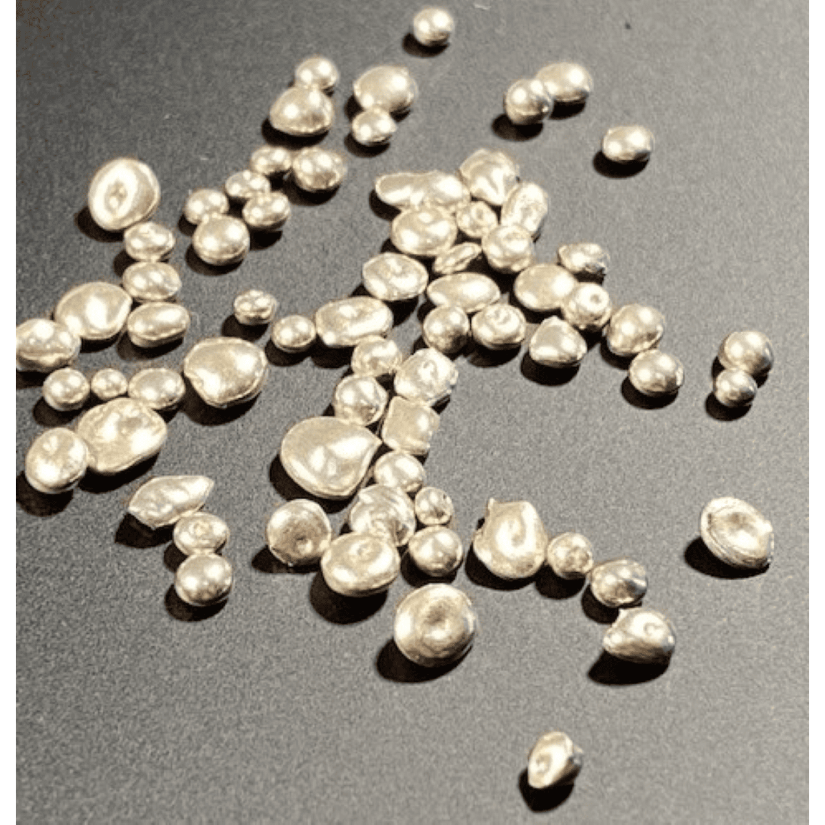 Small white gold pearls on a dark surface.