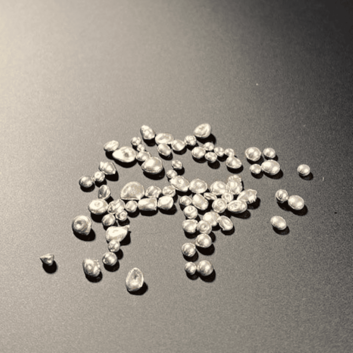 Pure white freshwater pearl grains on dark surface.