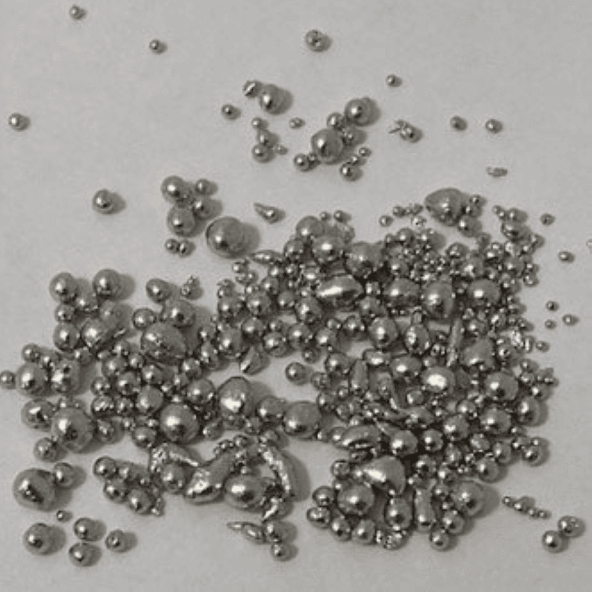 Shiny silver metal balls scattered on a plain background, viewed from above.